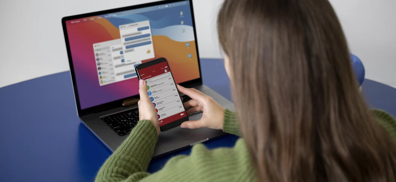 Woman looking at applications on her phone and her laptop